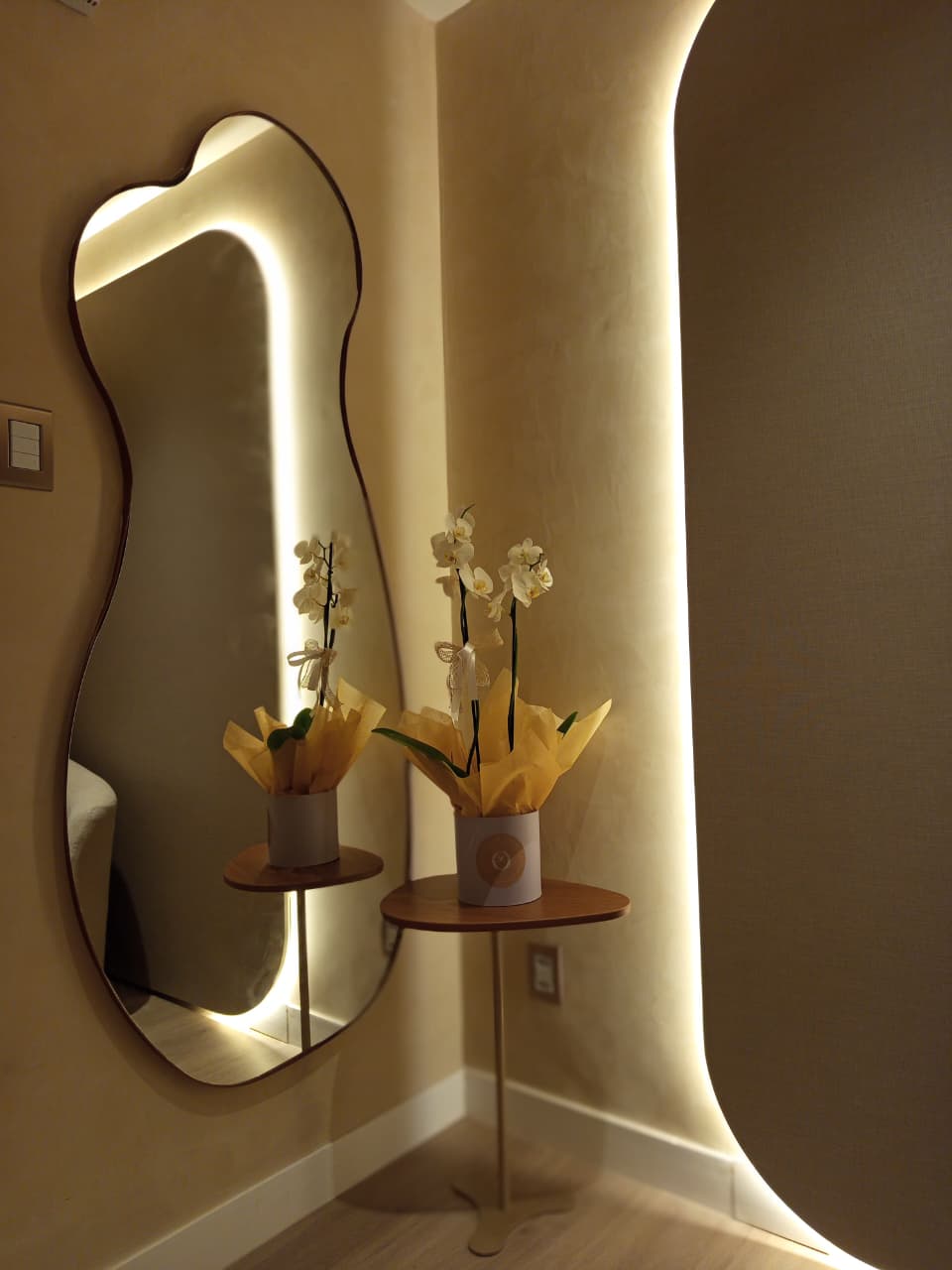 Detalhe do espelho e da orquídea branca na recepção, junto ao painel iluminado.